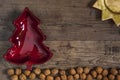 Red bowl in christmas tree shape and sun plate on ground of walnuts, rustic wooden floor background