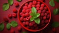 A red bowl filled with raspberries and green leaves. Generative AI image. Royalty Free Stock Photo