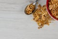 A red bowl on full of granola with a spoon on white wood table, Royalty Free Stock Photo