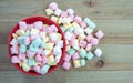 Red bowl overflowing with pastel butter mints on a wood background