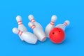 Red bowling ball crashing white falling pins on blue background Royalty Free Stock Photo