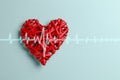 Red braided heart and cardiogram line on blue table