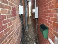 Red brick alley with electrical cables and meters