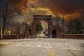 A red brick arch at the entrance of at the Oakland Cemetery with bare winter tree, lush green trees and plants