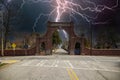 A red brick arch at the entrance of at the Oakland Cemetery with bare winter tree, lush green trees and plants