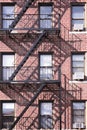 Red brick Bronx building with black metal fire escape and shadow background Royalty Free Stock Photo