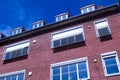 Red brick city building with several white windows on facade and roof Royalty Free Stock Photo