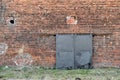 Red brick exterior wall of old factory with iron gates. Royalty Free Stock Photo