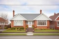 red brick home, white dormers, symmetrical windows, tidy hedges