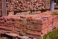 Red brick packed in stack are stored on ground outdoors at a hardware store warehouse. Building bricks on pallet on an