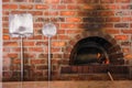 A red brick Pizza Oven and two pizza peels