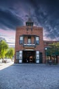 The red brick Plaza Firehouse surrounded by lush green trees at El Pueblo de Los Angeles Historical Monument with powerful clouds Royalty Free Stock Photo