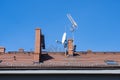 Red brick roof with chimneys and tv antennas on a clear blue sky Royalty Free Stock Photo