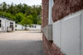 Red-brick school building corner with white trim and gray stone accent - pavement, school portable classrooms, trees in background