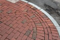 Red brick sidewalk corner with sweeping curb beside asphalt street Royalty Free Stock Photo