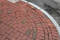 Red brick sidewalk corner with sweeping curb beside asphalt street