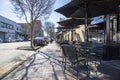 A red brick sidewalk dining area with black metal tables, chairs and umbrellas with cars parked along the street Royalty Free Stock Photo