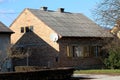 Red brick small old unfinished urban family house with yellow dilapidated wooden window blinds and without facade next to tall