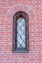 Red Brick Wall Of The Building With Wooden Window Behind The Metal Lattice