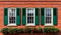 Red Brick Wall with Three Windows and Green Shutters adorned with Flower Boxes building Royalty Free Stock Photo