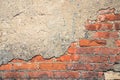 Red brick wall half covered with cement. Concrete covering, peeling off from old age, exposed rough brickwork Royalty Free Stock Photo