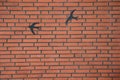 Red brick wall with metal shaped birds attached to it Royalty Free Stock Photo