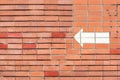 Red brick wall with a painted white arrow pointing in the direction Royalty Free Stock Photo