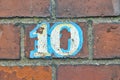 A red brick wall, painted with a white and blue framed number ten Royalty Free Stock Photo