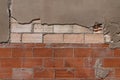 Red brick wall under damaged plaster background texture with cracked grey concrete Royalty Free Stock Photo