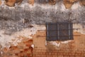 Red brick and white plaster exterior wall with barred and boarded window