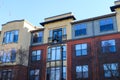 a red brick and yellow apartment building with bare winter trees, and tall curved black light posts in front with blue sky Royalty Free Stock Photo