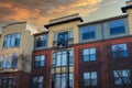 A red brick and yellow apartment building with bare winter trees, and tall curved black light posts in front Royalty Free Stock Photo