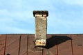 Red bricks dilapidated narrow chimney with parts of cracked broken facade and visible metal protection sheet