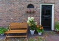Red bricks house faÃÂ§ade with bench, door and flowers Royalty Free Stock Photo