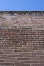 Red brickstone wall under blue sky (low angle view), use: background, wallpaper, texture Royalty Free Stock Photo