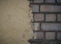 Red brickwork underneath concrete wall. Textured suface. Half painted wall. Background. Cracks and roughness Royalty Free Stock Photo