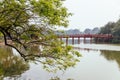 Red Bridge at Hoan Kiem Lake with tress and reflected shadow and branches in foreground in Hanoi, Vietnam