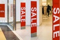 Red bright sale banner on anti-thieft gate sensor at retail shopping mall entrance. Seasonal discount offer in store