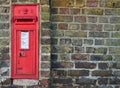 A red British post box in a wall with the royal cypher VR