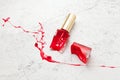 red broken nail polish bottle on marble background, dye color splash and suffusion Royalty Free Stock Photo