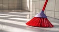 Red broom sweeping a tile floor in bright, natural light. Royalty Free Stock Photo