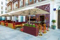 Red and brown building with tables under an umbrella over the top of it