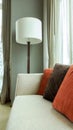 Red and Brown Decorative Pillows on a Casual Fabric Sofa with Big White Lamp in the Living Room
