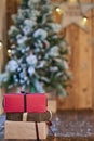 Red, brown and sandy yellow Christmas gifts near Christmas tree on wooden table Royalty Free Stock Photo