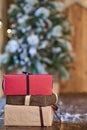 Red, brown and sandy yellow Christmas gifts near Christmas tree on wooden table Royalty Free Stock Photo