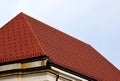 Red and brown steep clay tile roof. steep slope. Zink roof edge flashing. pale sky