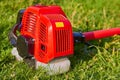 red brush cutter on the grass,a new brushcutter, a tool for mowing grass, lies on the green grass Royalty Free Stock Photo