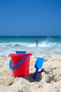 Red bucket and blue spade on sunny sandy beach Royalty Free Stock Photo