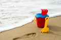 Red bucket with a shovel, a rake and a net on the beach Royalty Free Stock Photo