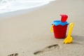 Red bucket with a shovel, a rake and a net on the beach Royalty Free Stock Photo